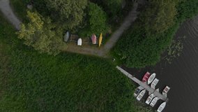 Aerial drone pull up camera flies high from a boat berth dock near trees and grass