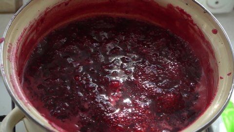 Cook raspberry jam in a pan in the sunlight. Bright colors. Sweet jam. Cooking jam