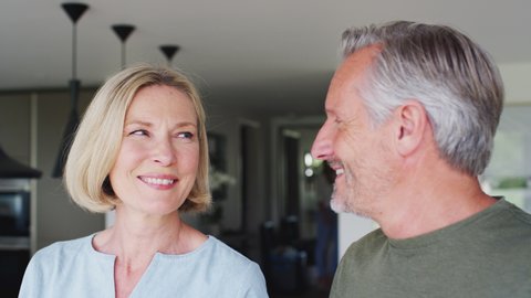 Senior Couple Standing In Kitchen And Talking Together