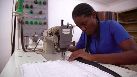 ZAMBIA - CIRCA 2018 - A woman worker sews a garment by hand in a sweatshop in Zambia, Africa.