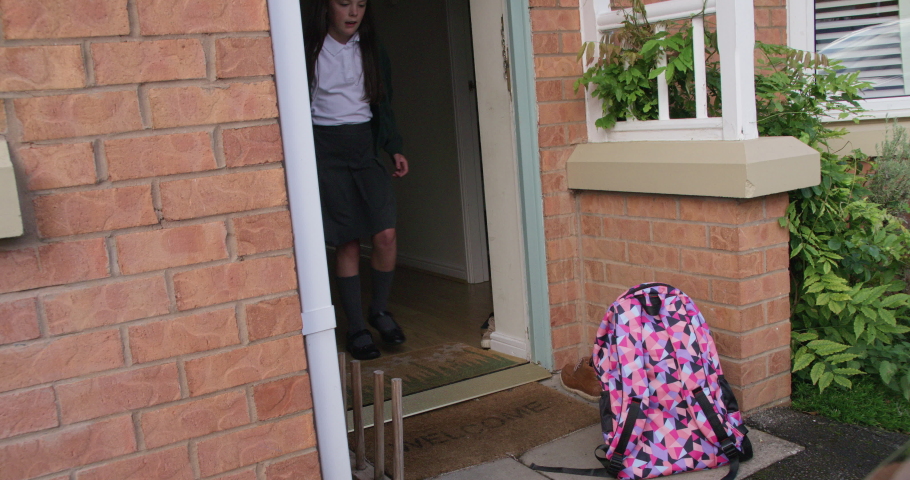 School girl rushing out the front door and off to school