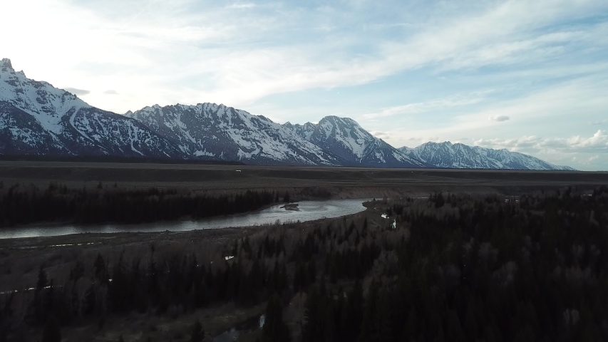 Cinematic Aerial Overview of Snake River in Valley Under Grand Teton Mountain Range in Wyoming, USA