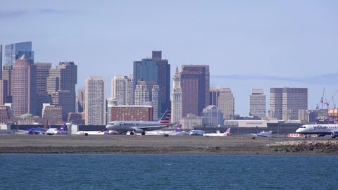 BOSTON, MASSACHUSETTS - CIRCA 2018 - Planes taxi on a runway at Logan International Airport Boston with city skyline background.