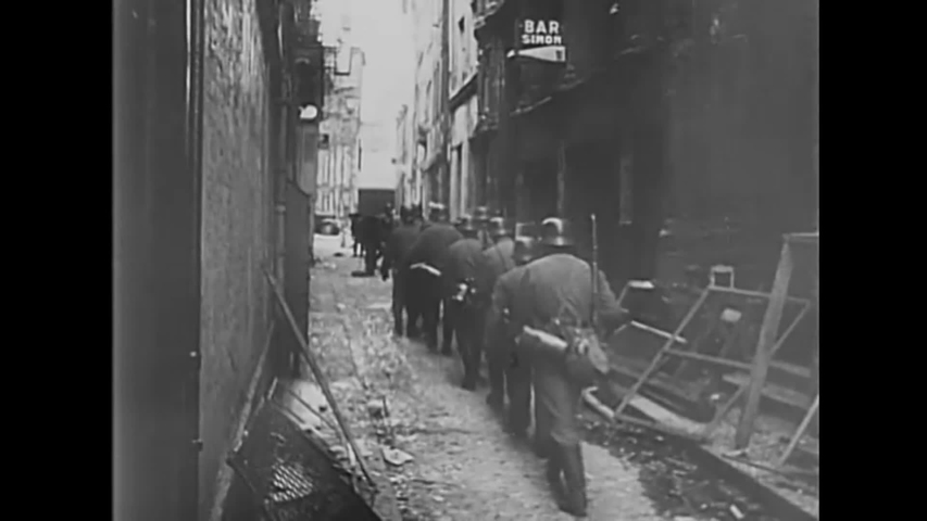 CIRCA 1940 - German soldiers walk through the wreckage of a French city they destroyed, and put out a burning cathedral.