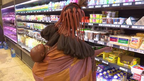 OPUWO, NAMIBIA - CIRCA 2018 - Astonishing shot of tribal African Himba woman shopping in a modern supermarket contrast of old and modern life.