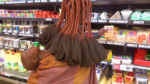 OPUWO, NAMIBIA - CIRCA 2018 - Astonishing shot of tribal African Himba woman shopping in a modern supermarket contrast of old and modern life.