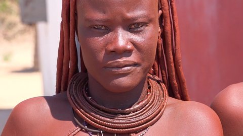 NAMIBIA - CIRCA 2018 - Beautiful Himba African tribal woman face with mud hair style and dreadlocks and round necklaces.