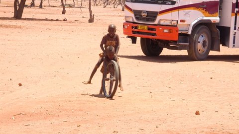 NAMIBIA - CIRCA 2018 - Poor African children play with a bicycle wheel as a toy in a Himba village on the Namibia Angola border.