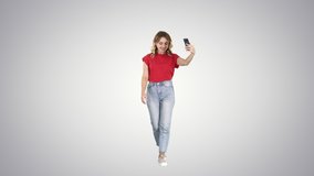 Cheerful young hipster girl streaming video for internet blog while walking on gradient background.