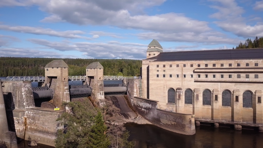 Aerial, pan, drone shot, overlooking the closed flood gates and details on the Solbersfossen hydroelectric power station dam, at Glomma river, on a sunny, summer day, in Spydeberg, Ostfold, Norway