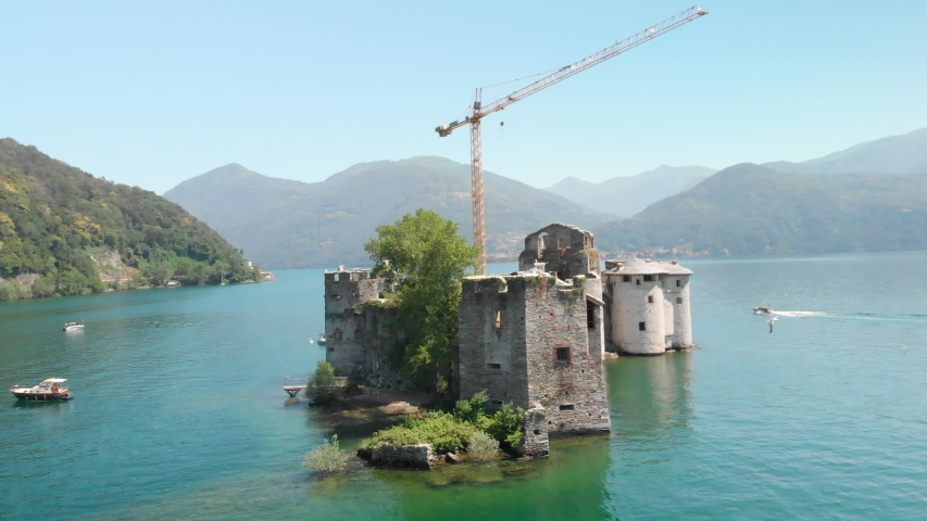 Aerial view of a ruin on a small island in the middle of Lake Maggiore, Italy. Birds flying in front of the camera