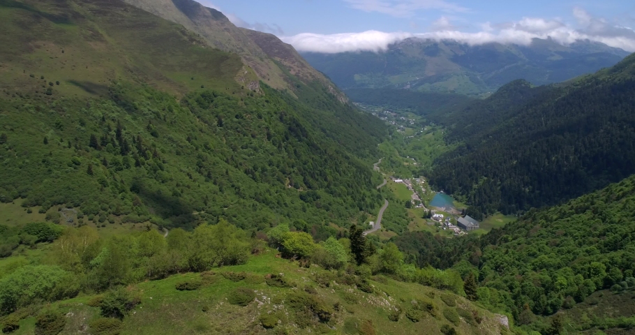 Town in Pyrenee mountains, aerial, drone shot, panning around a hill, overlooking the Artigues village, in a valley, on a sunny, summer day, at Col du Tourmalet pass, in the Hautes Pyrenees, in France