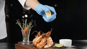 Slow motion food video. Restaurant dish serving. Lemon or lime juice dripping on flambe-style cooked shrimps put on brown board. Close up of chef hand squeezing lime . juice dribbling out of fruit. hd