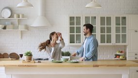Young happy active family couple dancing laughing together preparing food at home, carefree joyful husband and wife having fun cooking healthy romantic dinner meal listen to music in modern kitchen - Powered by Shutterstock - Get 15% off with code: PIKWIZARD15