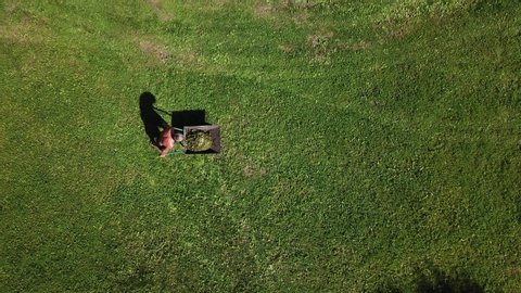 man pulls a wheelbarrow with garbage top view
