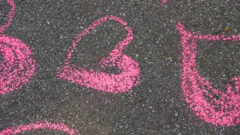 Hearts pattern of many pink hearts drawn on grey texture of sidewalk. 4k video footage.