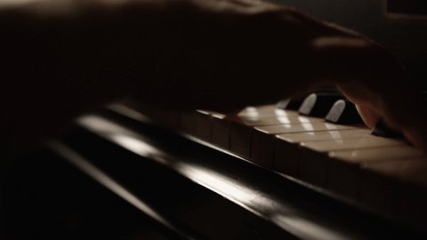Hands of a male piano player on grand piano in low key light