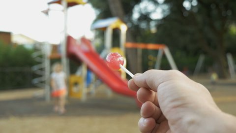 Stranger on playground offers candy to child. Kids in danger. Children safety protection. Suspicious adult man spying on kids and calls a child to himself. kidnapping concept, first-person view