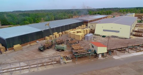 Automated log sorting at a sawmill, aerial view. Crane unloads logs to the sorting line
