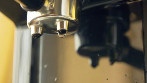 Water pours through the portofilter of the coffee machine. Professional brewing coffee. Making espresso. Close-up