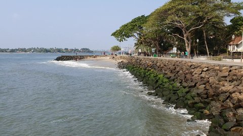 KERALA, INDIA - MARCH 24, 2019:  Clear sunny sky background and greenery on Fort Kochi beach Vypeen Island in cochin. Breakwaters to reduce coastal erosion, man made big huge rock fence in sea