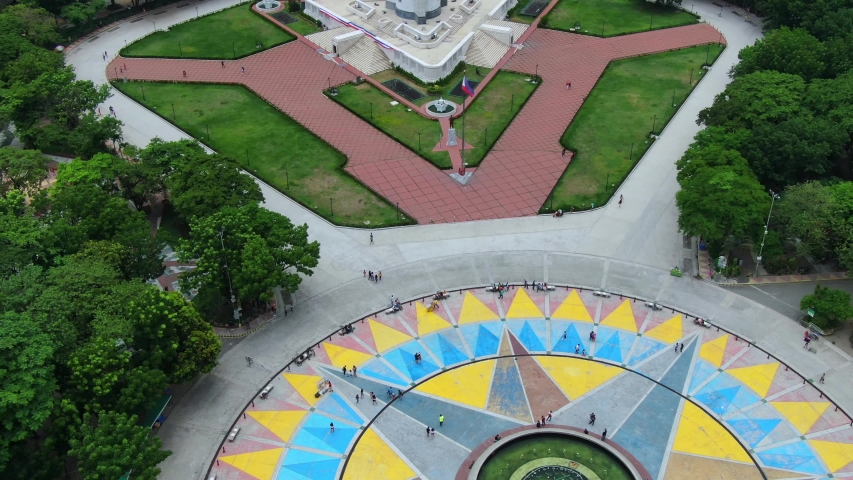 View of the Quezon Memorial Circle and people walking and sitting at the park.