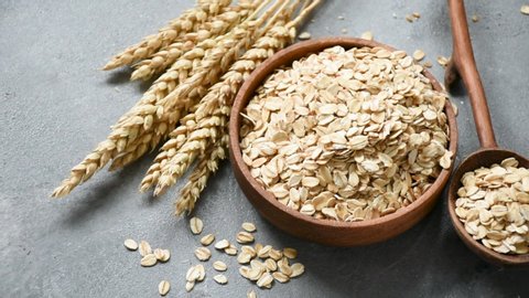 Slow motion of oat flakes or rolled oats falling in wooden bowl. Wholegrain cereals. Concept of healthy lifestyle, clean eating, dieting