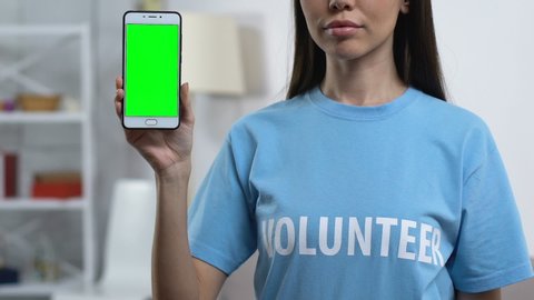 Lady volunteer demonstrating prekeyed smartphone to camera, charity application