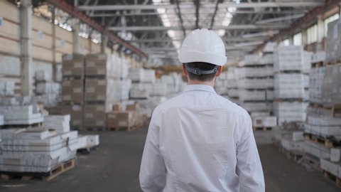 Follow footage of employees male warehouse worker engineer in hard hat working. walking through logistics center warehouse factory construction site logistics architect businessman man builder indoors