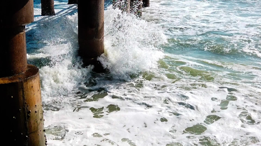 Slow Motion shot of waves crashing onto rocks. Waves crashing onto rocky shore. Stormy ocean.