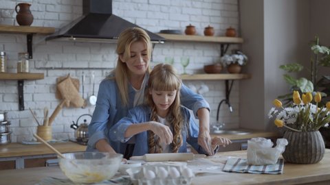 Mom and daughter roll out the pizza dough with a wooden rolling pin. The concept of a happy family. 4K