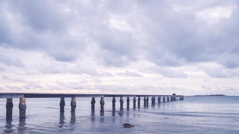 Anse Vata Bay, Noumea, New Caledonia -August 4, 2019: 4k Timelapse Video -People walking on the pier at Anse Vata beach with mesmerizing clouds moving in the background at sunset in French Polynesia.