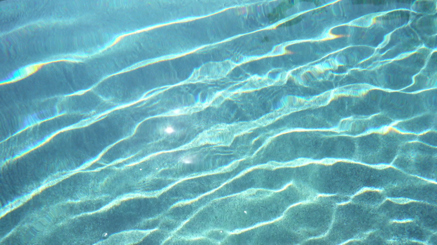 Footage of a pure blue swimming pool at daytime with awesome sunny reflection waves.