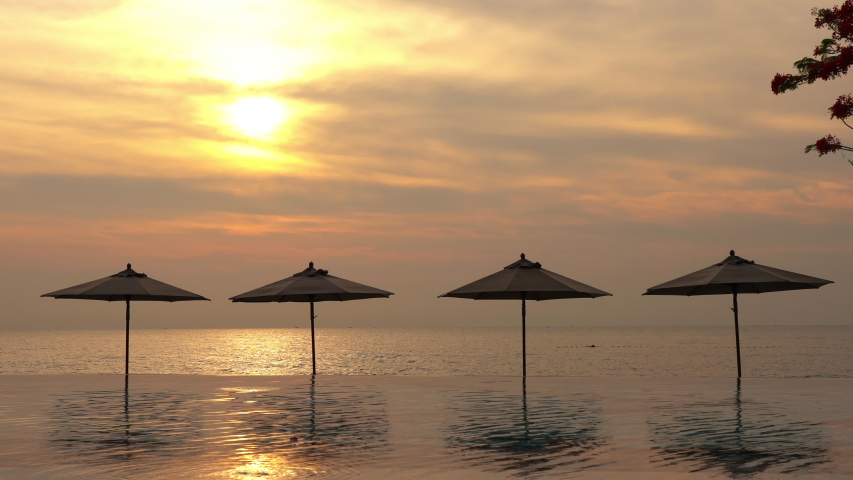 Footage of a serene golden hour beach with perfect relaxing umbrellas.