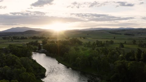 Aerial view of a beautiful sunrise over mountains along a snaking river. Shot above the North Platte River in Wyoming, USA | 4K
