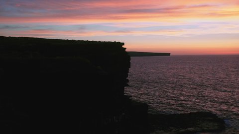 PANNING RIGHT Dramatic cliffs silhouette and sea on spectacular sunset in Ireland