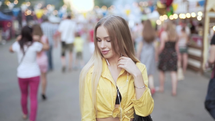 Beautiful young lady listening to music at festival and looking around