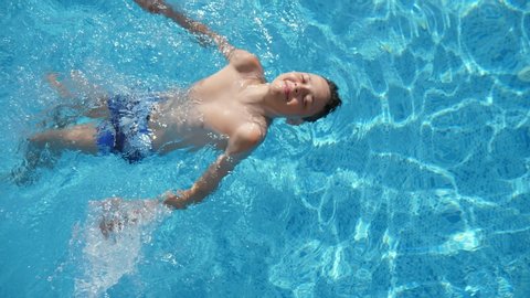 Small boy in a mask swimming underwater in paddling pool in summer in slo-mo