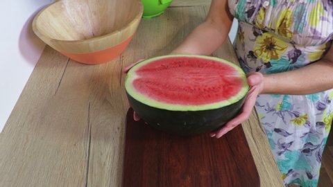 Woman cutting red watermelon on table