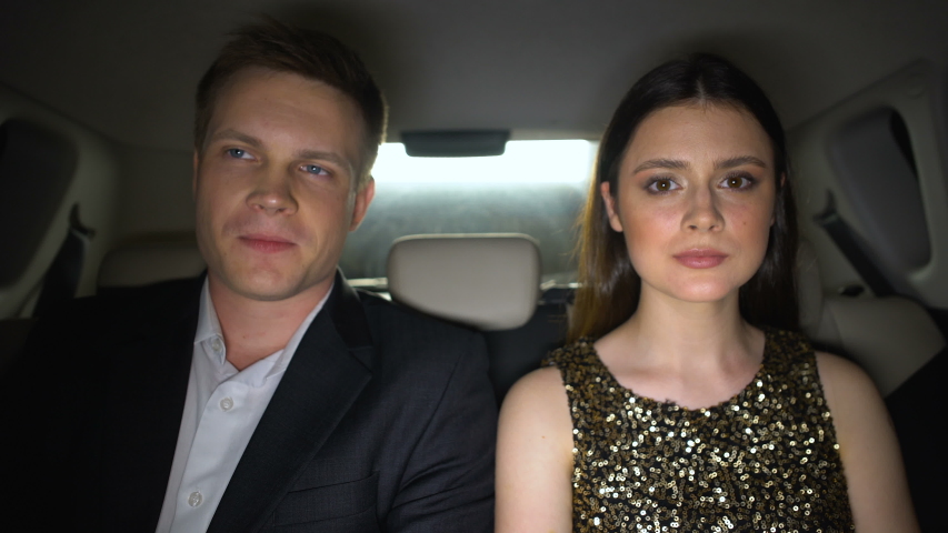Smiling celebrities sitting on back seats and looking at camera, superstars