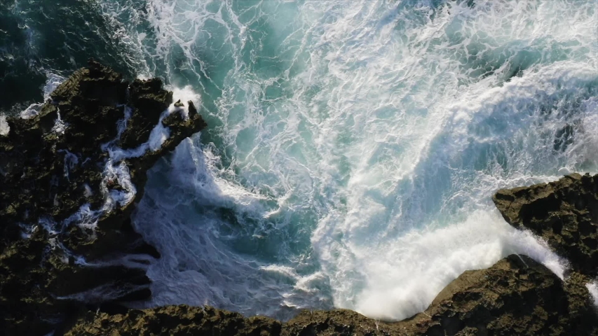 Amazing top aerial slow motion view of azure ocean and giant waves crashing at rocky cliff with splashing and white foam. Bali island, Indonesia Royalty-Free Stock Footage #1035619751