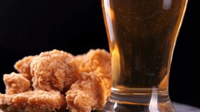 Grilled chicken wings and a glass of beer on black. 4K rotation