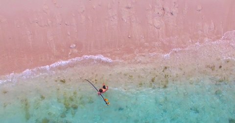 Pacitan Indonesia 22 August 2019 : Aerial view of Aerial young man exercising sup board in turquoise tropical clear water in pink beach