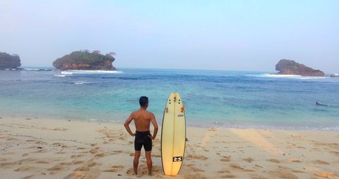 Pacitan Indonesia 22 August 2019 : Aerial view of Aerial young man exercising sup board in turquoise tropical clear water in pink beach