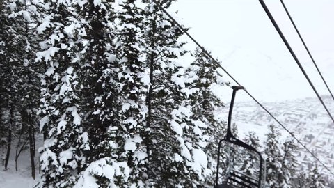 Ski lifts can be seen working their way up the mountain as it continues to snow.: stockvideo