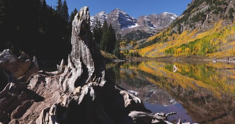Maroon Bells Aspen Colorado. The Rocky Mountains reflect perfectly in Maroon Lake during peak fall colors. Motion shot, 4K footage shot on a cinema slider.