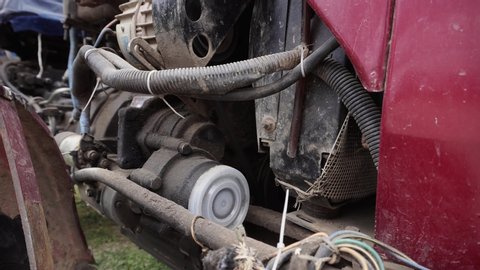 An opened bonnet of a red tractor and its old engine with many wires.