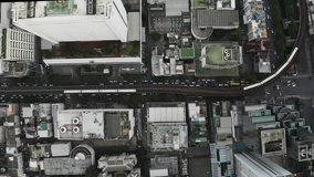 4K Aerial Drone Footage overhead top down view of a city train transportation moving through the tracks over city street traffic in downtown Bangkok Thailand.
