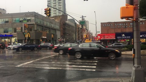New York, New York / USA - Aug 18 2019: Traffic on rainy day; corner of Essex and Delancey Street across from old Essex Market,  heading in the direction of the Williamsburg Bridge.