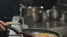 Chef holding frying pan in hand and mixes mushrooms, onions, peppers and chicken. Slow Motion Video